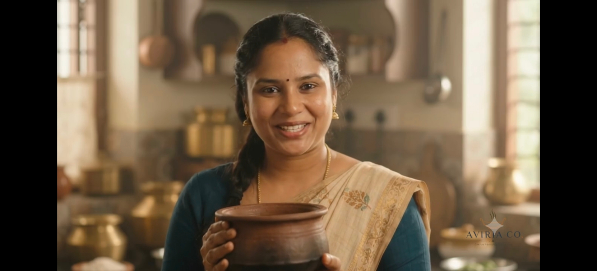 Chef Vijayalakshmi in the kitchen holding a clay cooking pot